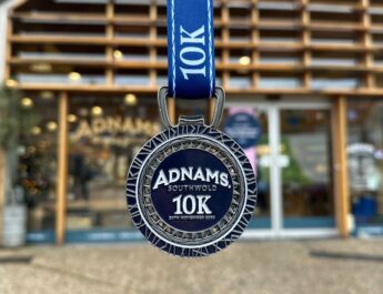 Adnams 10k Run 2025 medal hanging ready outside of the Adnams Southwold store, an upcoming event in Southwold.