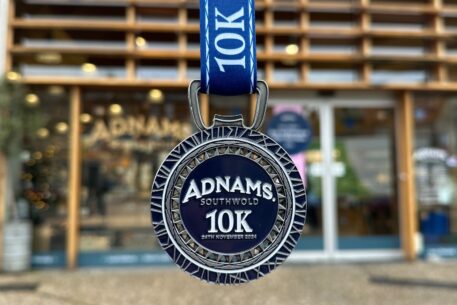 Adnams 10k Run 2025 medal hanging ready outside of the Adnams Southwold store, an upcoming event in Southwold.